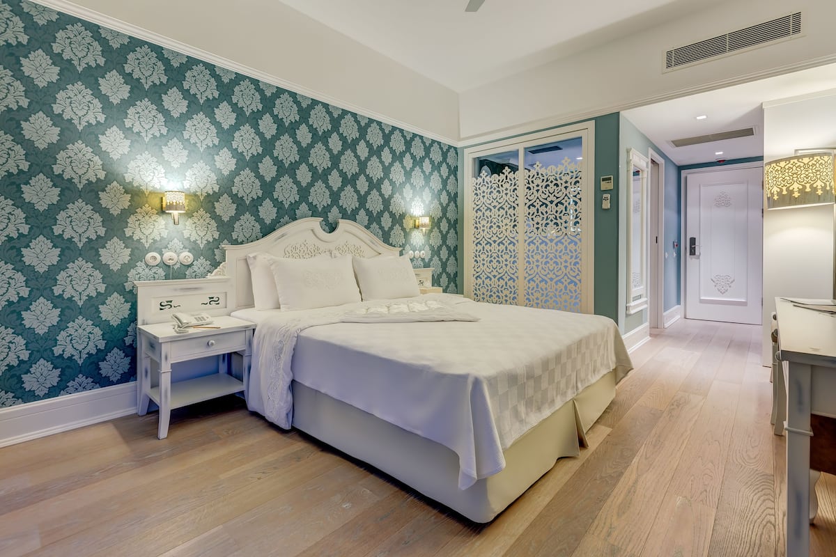 A bedroom with a large bed, a nightstand, and a wall-mounted light fixture.