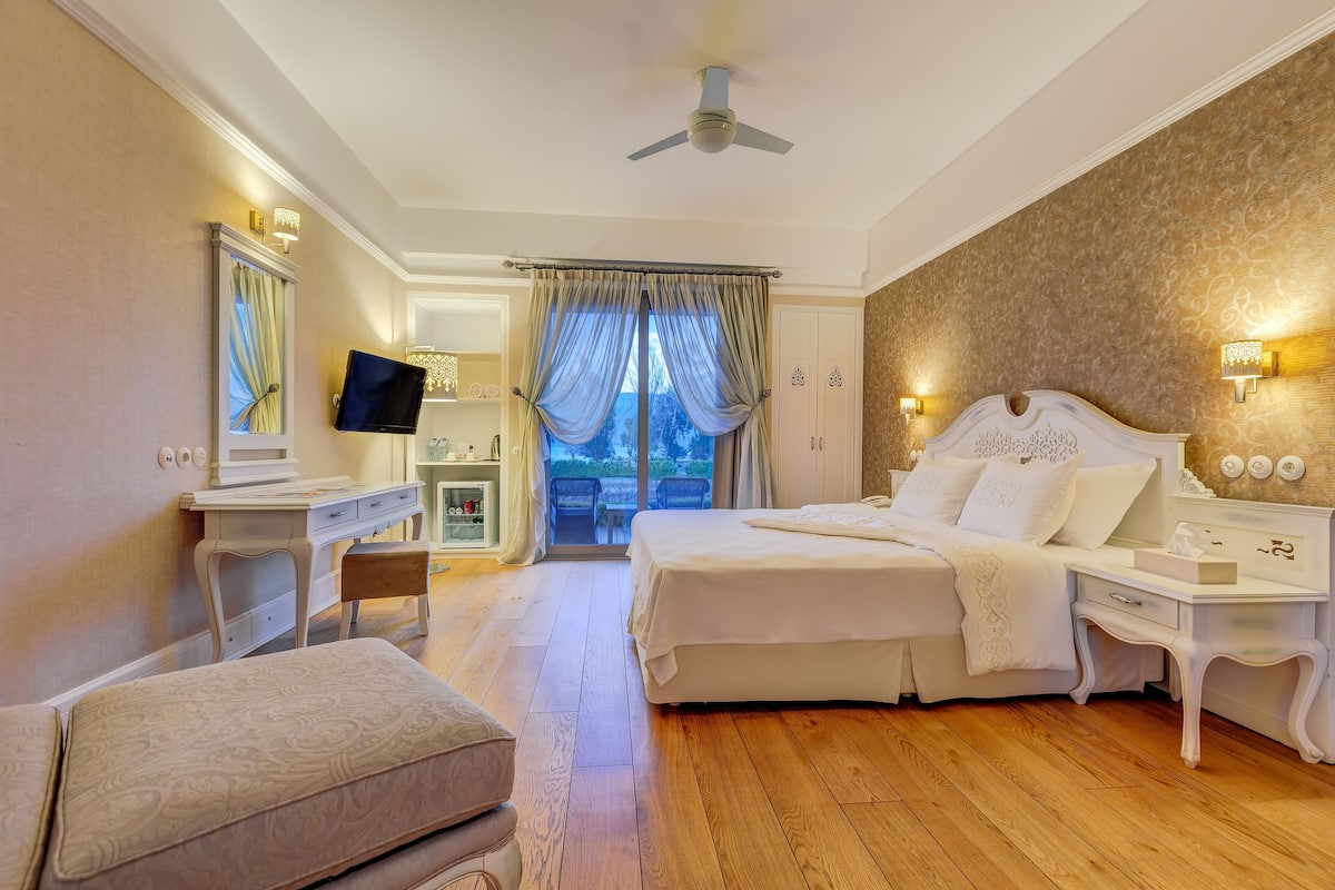 A hotel room with a bed, a desk, a chair, a television, and a view of the outdoors.