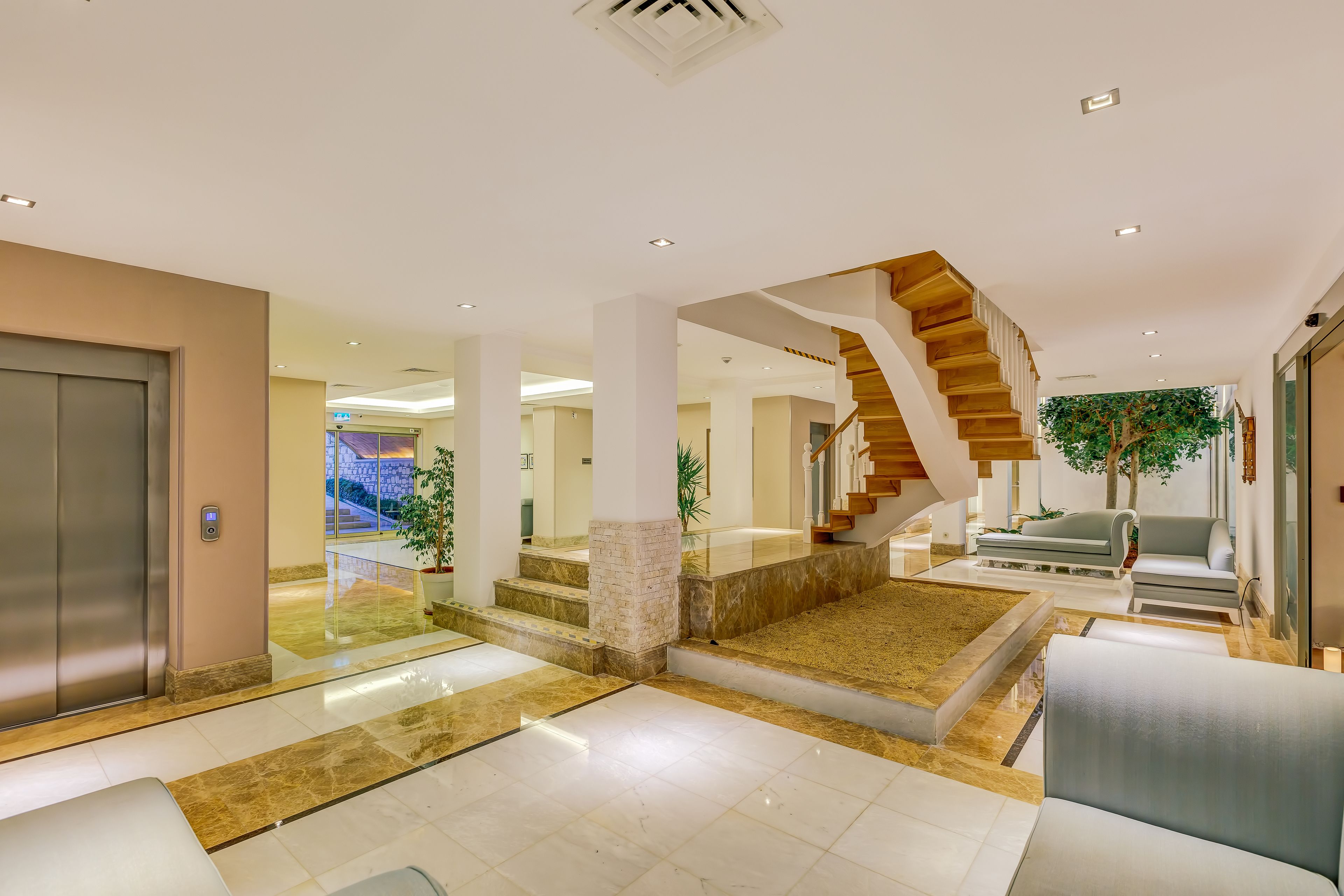 A spacious lobby with a marble floor, a staircase, and a seating area.
