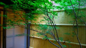 Um quarto em estilo japonês tradicional, com piso de tatame, tela shoji e cerca de bambu.