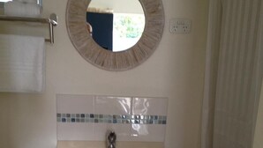 Un baño con un espejo redondo, un lavabo y un salpicadero de azulejos.