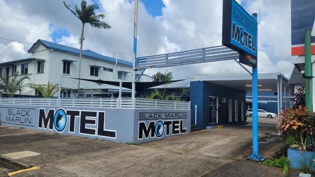 A motel with a prominent sign, a covered parking area, and a building with a blue roof.
