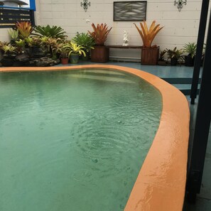 Una piscina al aire libre, sillones reclinables de piscina