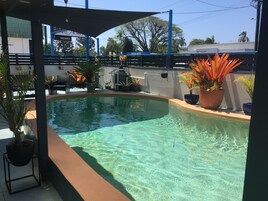 Una piscina al aire libre, sillones reclinables de piscina