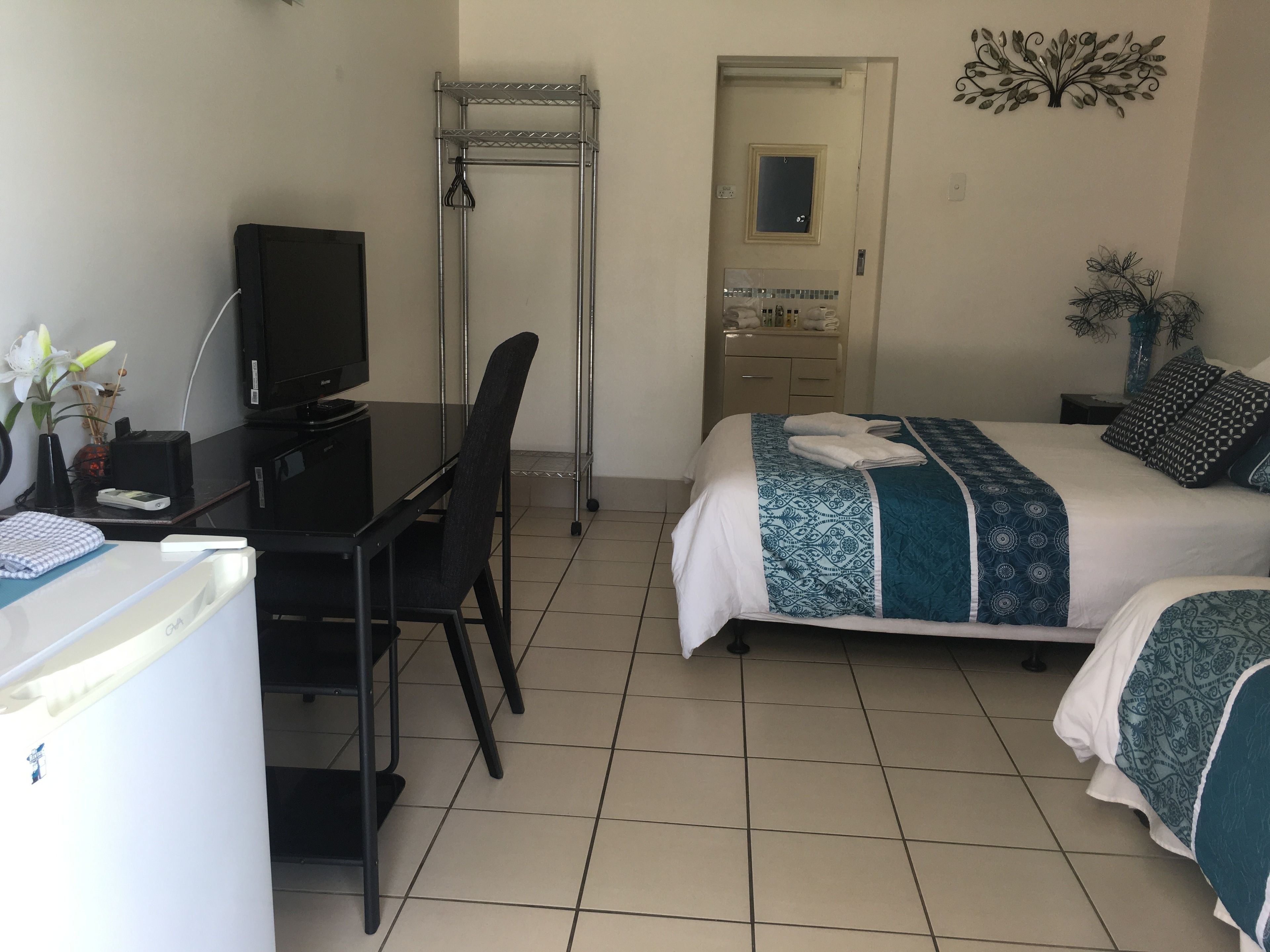 Habitación de hotel con escritorio, silla, cama y baño pequeño.