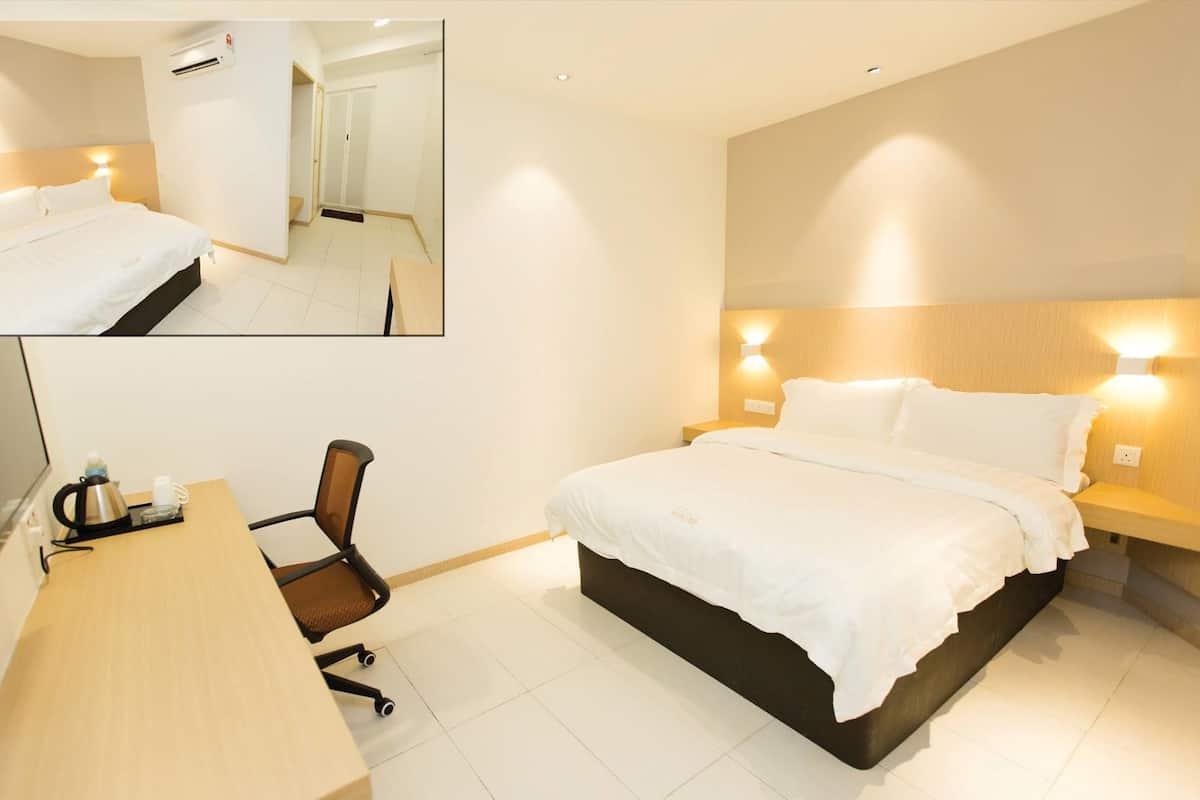 A hotel room with a bed, bedside tables, a desk with a chair, and a mirror.
