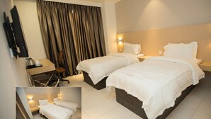 A hotel room with two beds, a desk with a chair, a TV mounted on the wall, and a window with curtains. - Extreme Boutique Hotel (Kluang)