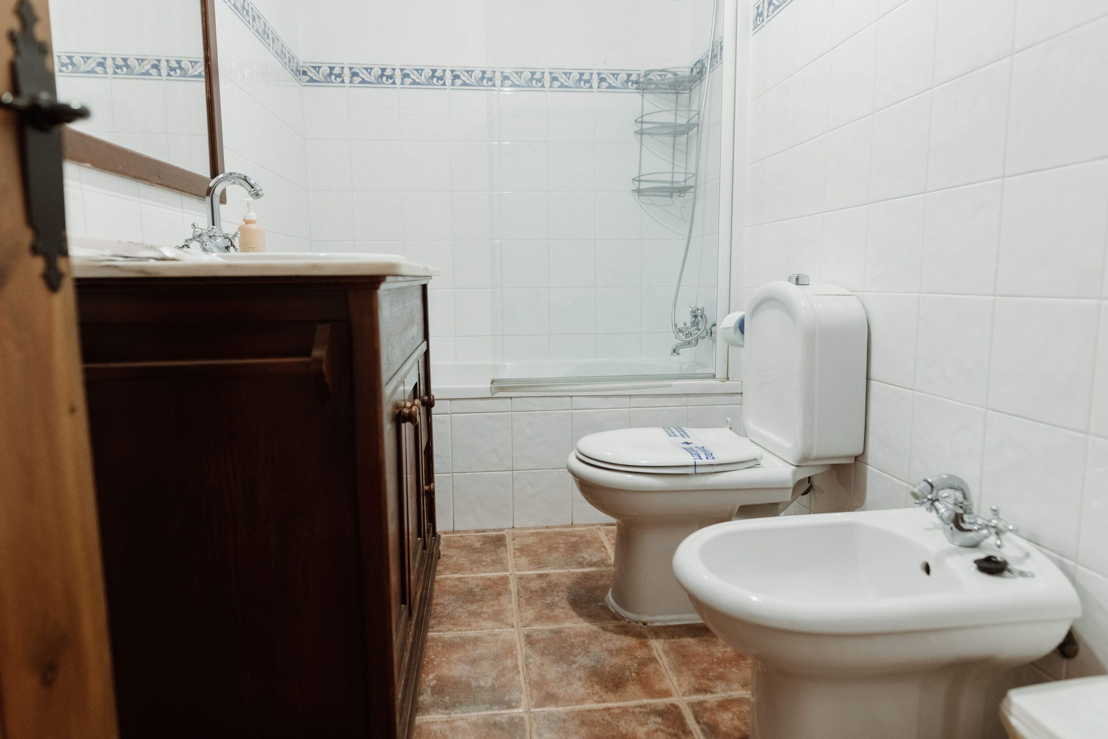 Un baño con lavamanos, inodoro, bidé y ducha.