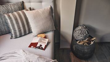 A neatly made bed with pillows, a book, and a decorative ball of yarn.