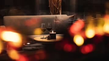 A cozy indoor setting with a sofa, a table with two glasses of wine, and a lit candle.