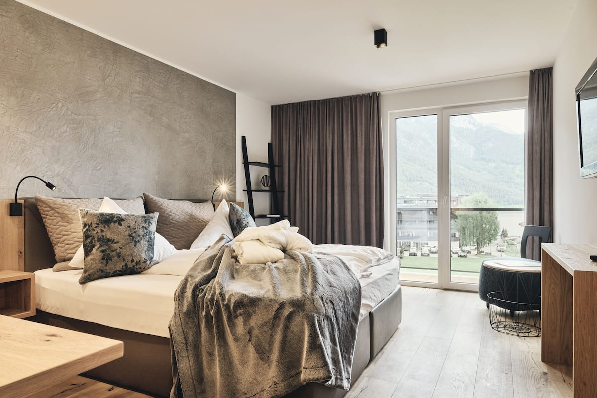 Un dormitorio moderno con una cama grande, un escritorio y vistas a montañas a través de la ventana.