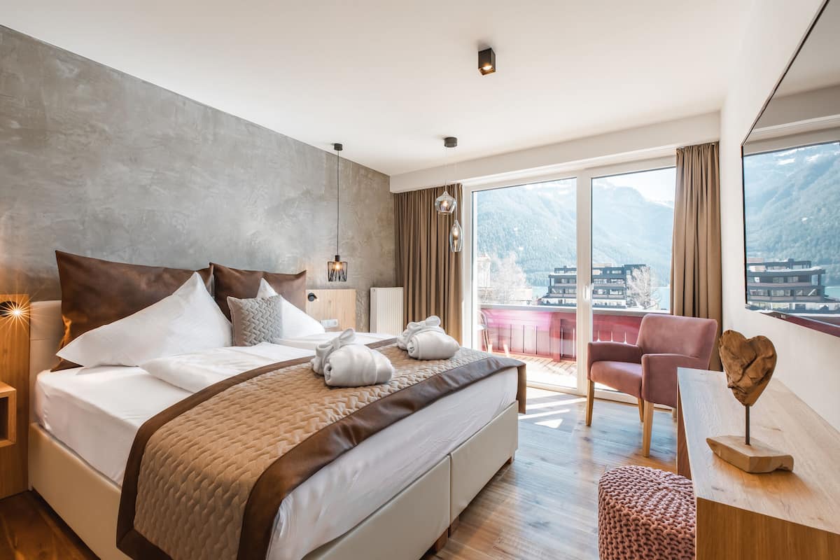 Una habitación de hotel moderna con una cama grande, un escritorio y vistas a montañas.