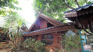 Una casa de madera tradicional con techo inclinado, un ventanal grande y una pared de piedra.