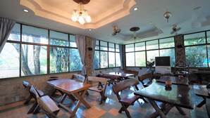 Un comedor espacioso con amplias ventanas, muebles de madera y una araña.