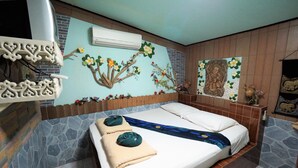 Habitación de hotel con cama, decoración mural, pared de piedra y unidad de aire acondicionado.