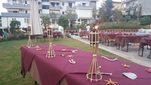 Outdoor dining tables with maroon tablecloths, starfish decorations, and wooden centerpieces.