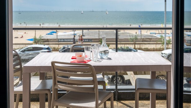 A table with chairs and a view of the beach and ocean. - Résidence Odalys de La Plage (Pornichet)