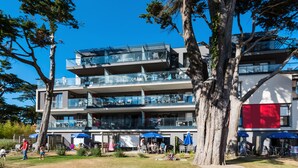 A modern multi-story building with balconies, outdoor seating, and a clear blue sky. - Résidence Odalys de La Plage (Pornichet)