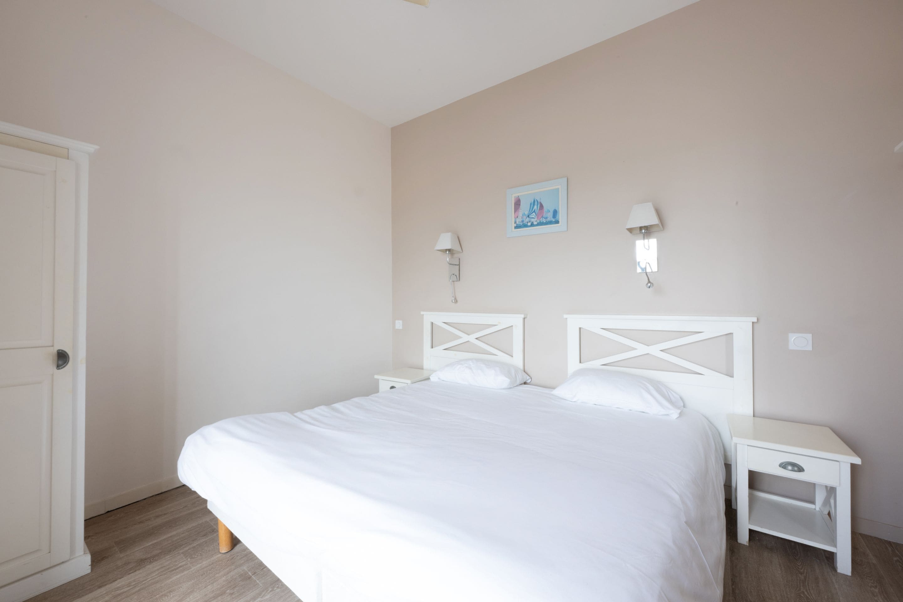 Een slaapkamer met een groot bed, twee nachtkastjes en een deur.
