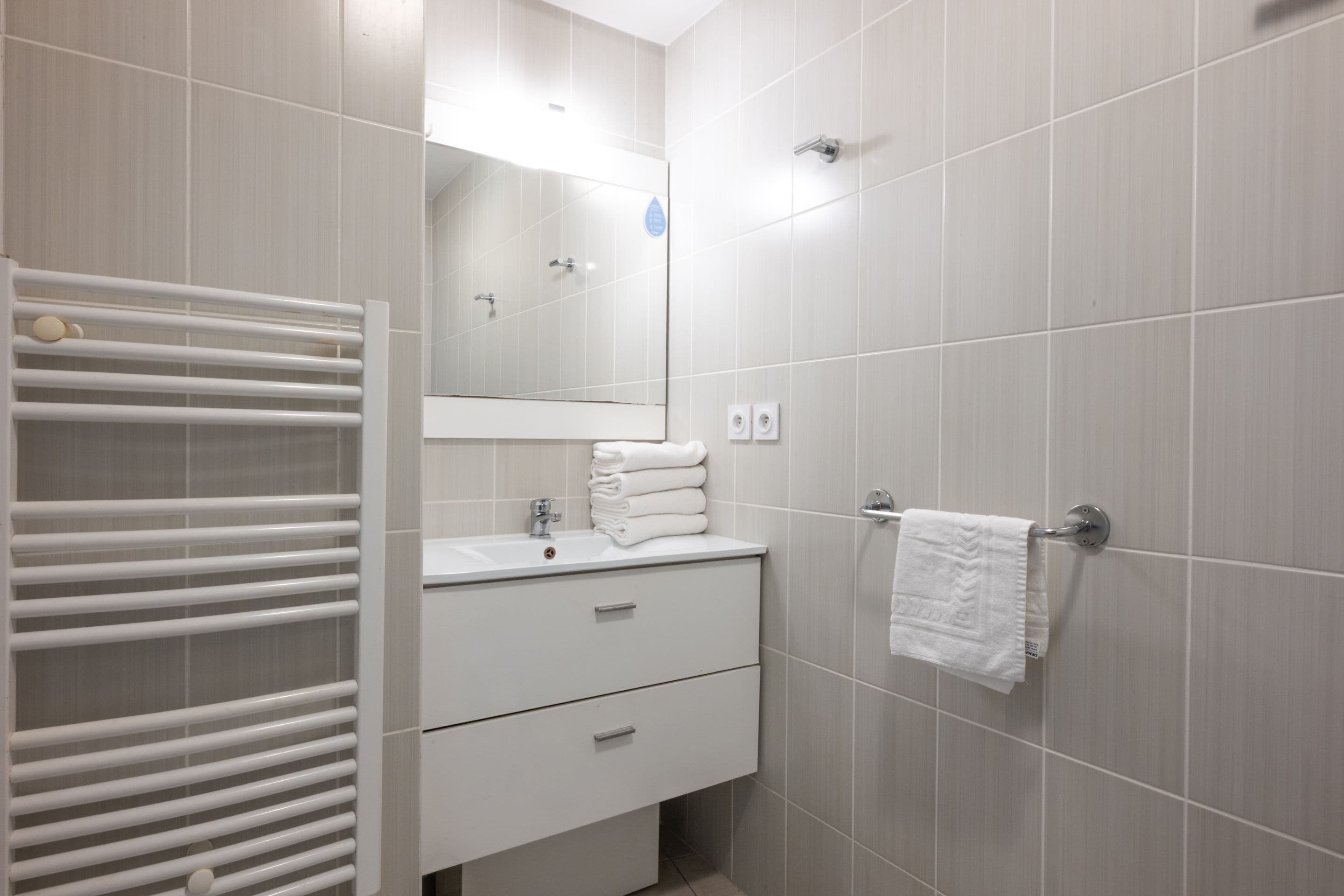 Ein modernes Badezimmer mit Waschbecken, Spiegel und Handtuchhalter.