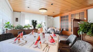 A dining area with a long table set for a meal, surrounded by chairs.