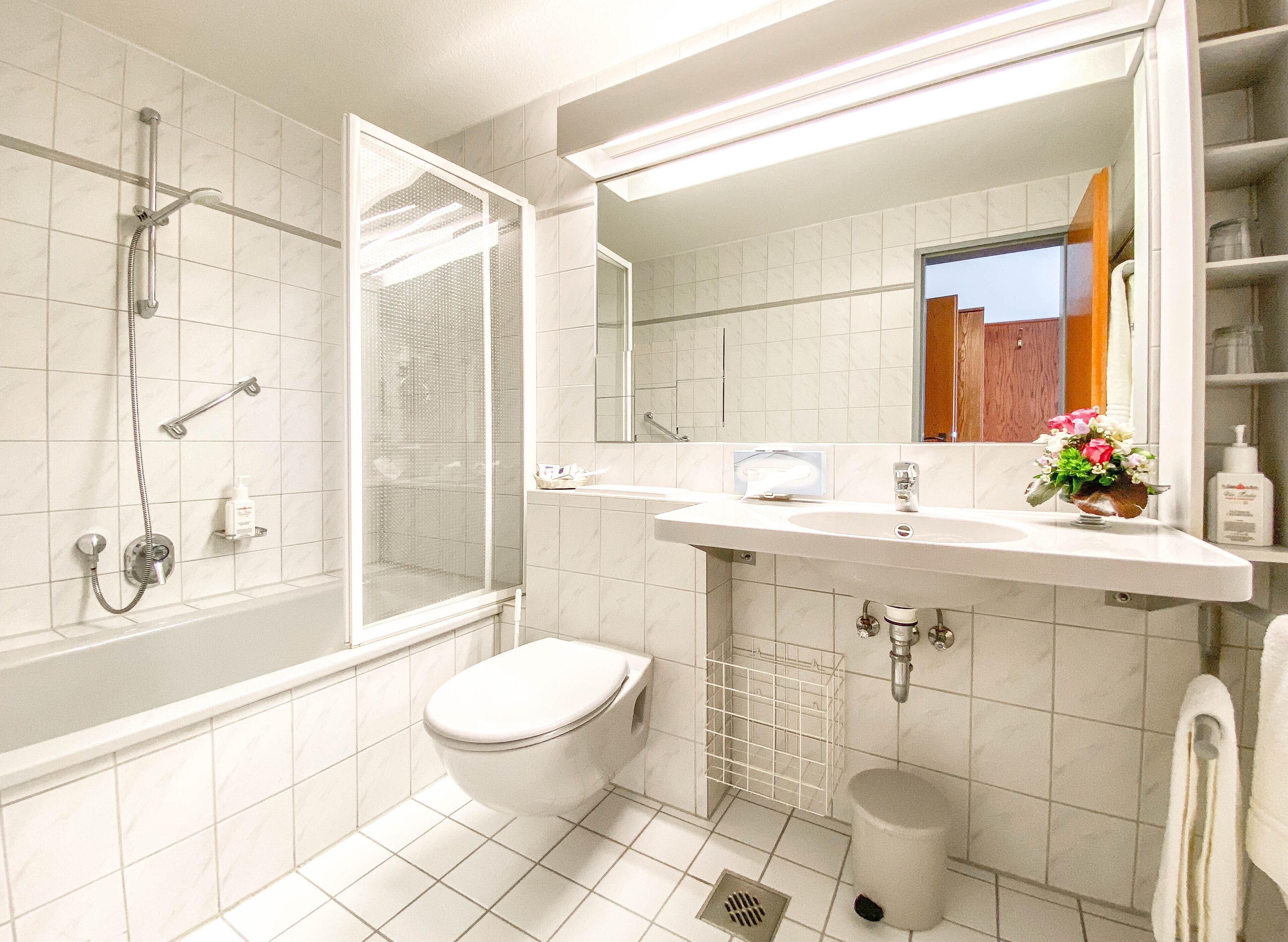 Un bagno con doccia, toilette, lavandino e specchio.