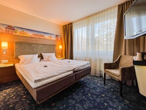 A hotel room with a large bed, a chair, a desk, and a painting of a cityscape on the wall. - Vier Linden Kiek In Hotel (Stade)