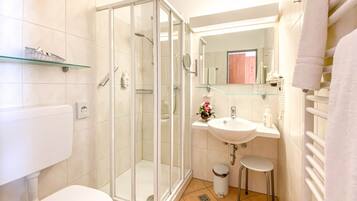 A bathroom with a glass-enclosed shower, a white sink, and a toilet.