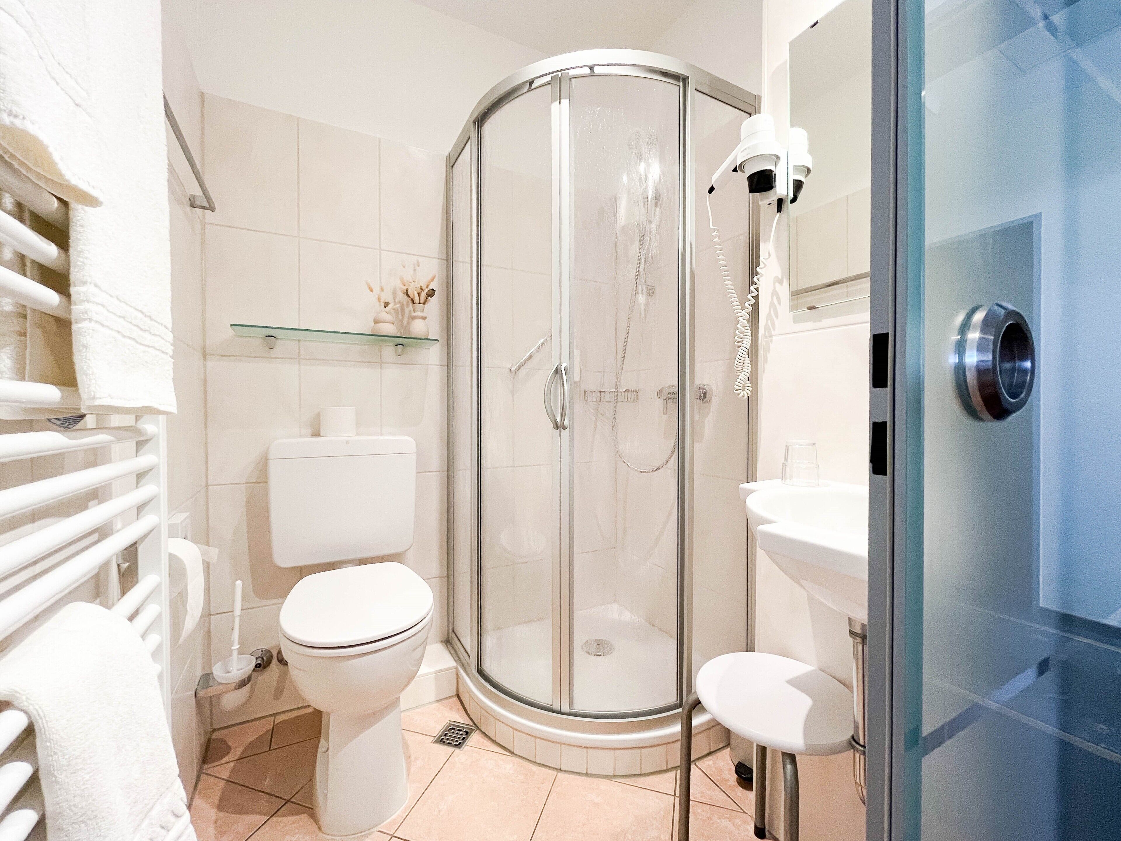 A modern bathroom with a glass-enclosed shower, a toilet, and a sink.