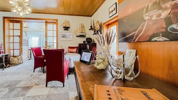 A hotel lobby with a wooden ceiling, red chairs, a reception desk, and nautical decor.
