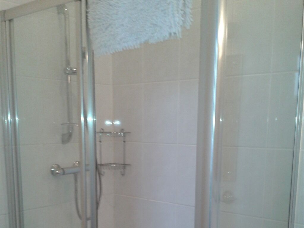 Ein Duschbereich mit Glasabtrennung und ein weißes, flauschiges Handtuch an der Wand.