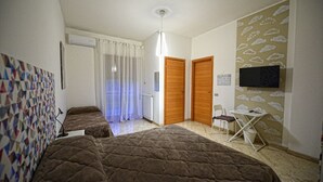 Habitación con dos camas, una mesita, una silla, televisión y un papel tapiz estampado.