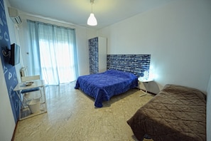 A bedroom with a bed, a bedside table, a lamp, a chair, and a window with curtains. - Aback (Bari)