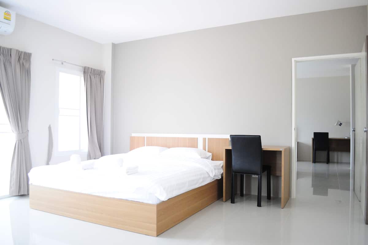 A modern hotel room with a wooden bed, a desk, and two chairs.