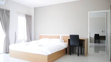 A modern hotel room with a wooden bed, a desk, and two chairs.