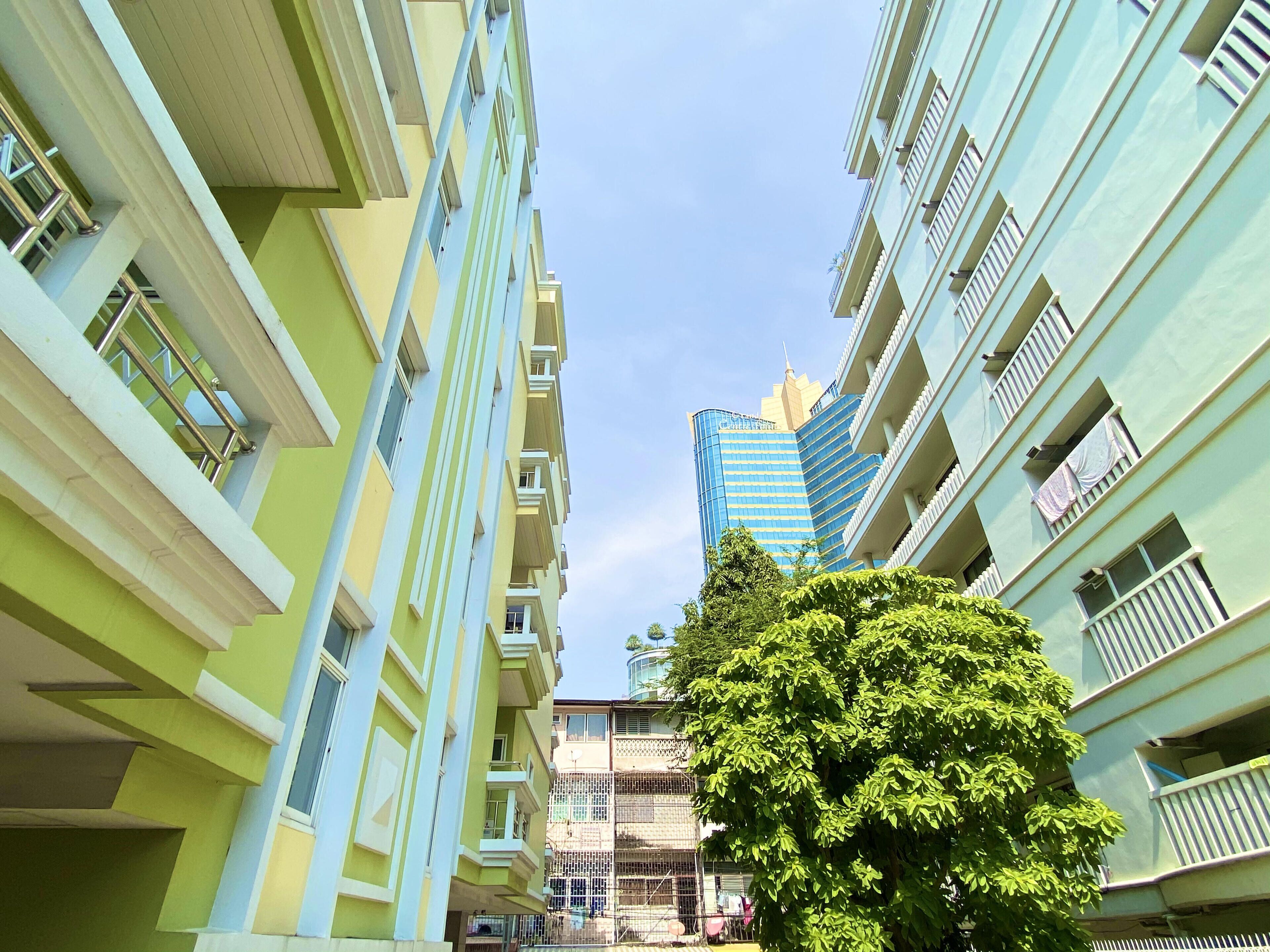 Un immeuble à plusieurs étages, doté de balcons, avec un arbre au premier plan.