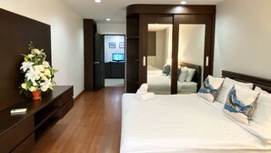 Een hotelkamer met een groot bed, een televisie in de hoek en een houten dressoir.