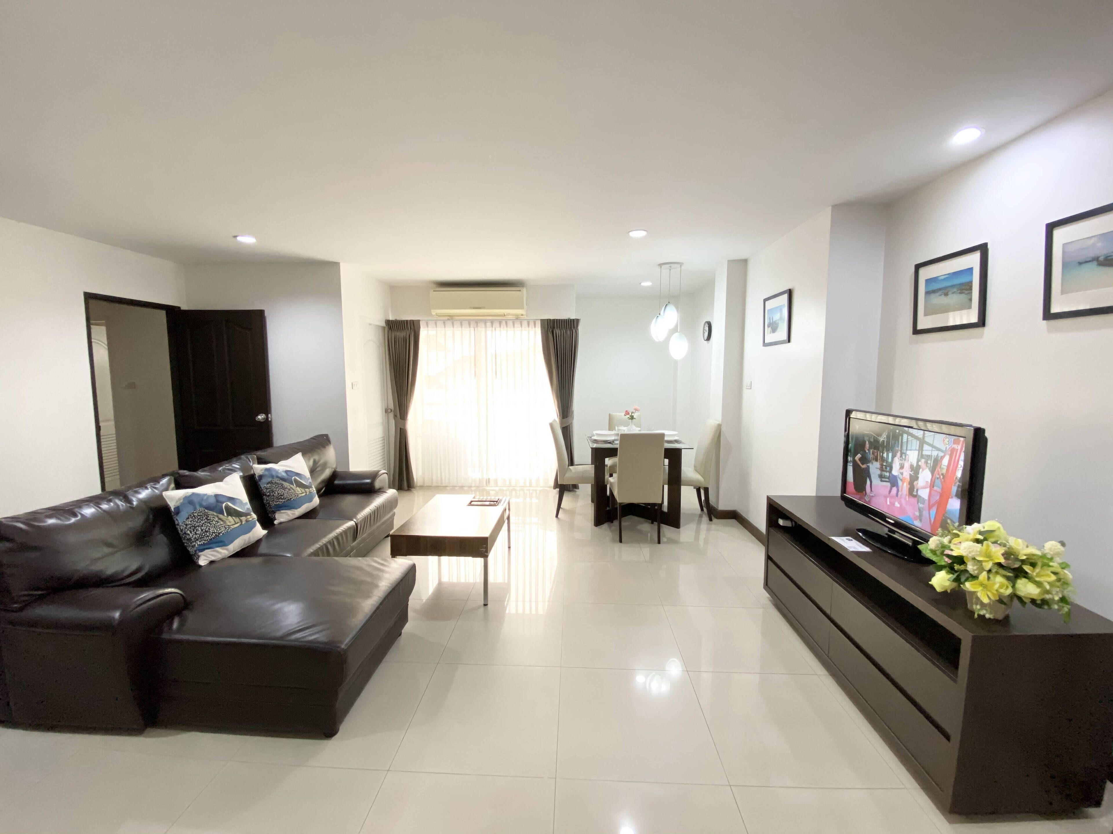 Una sala de estar moderna con un sofá de cuero, una mesa de comedor y un televisor.