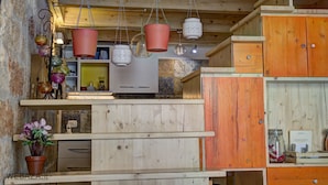 A rustic kitchen with wooden cabinets, hanging pots, and a potted plant. - B&B Frugis (Polignano a Mare)