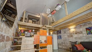 A rustic interior with wooden furniture, a staircase, and a stone wall. - B&B Frugis (Polignano a Mare)