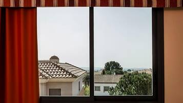 A window with a view of neighboring buildings and a clear sky.