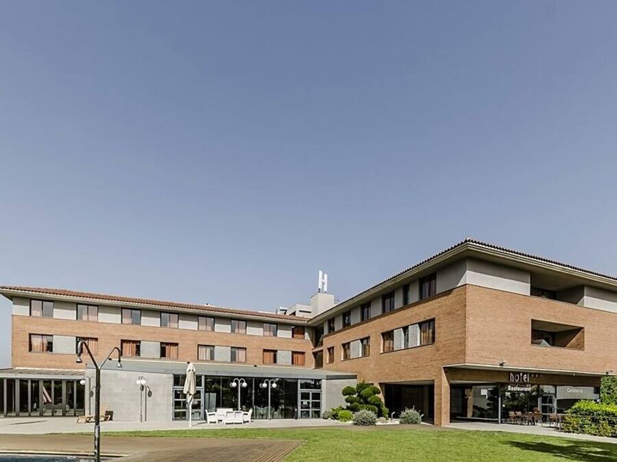 A modern hotel with a two-story structure, outdoor seating area, and a swimming pool.