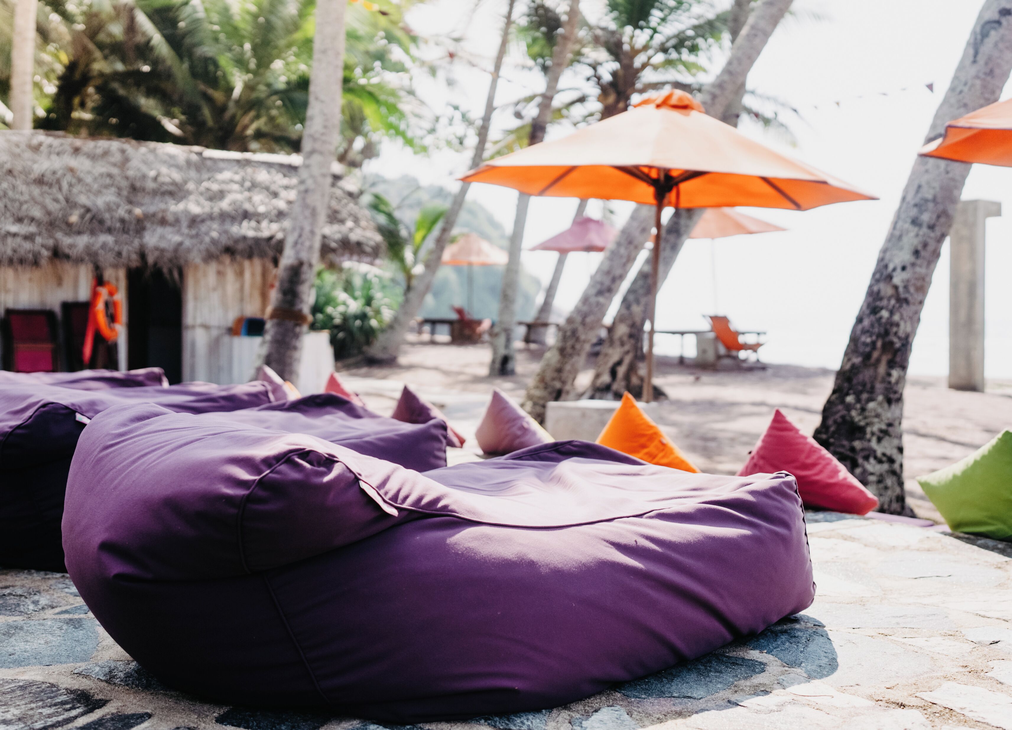 Outdoor seating with cushions, a thatched-roof structure, and umbrellas.