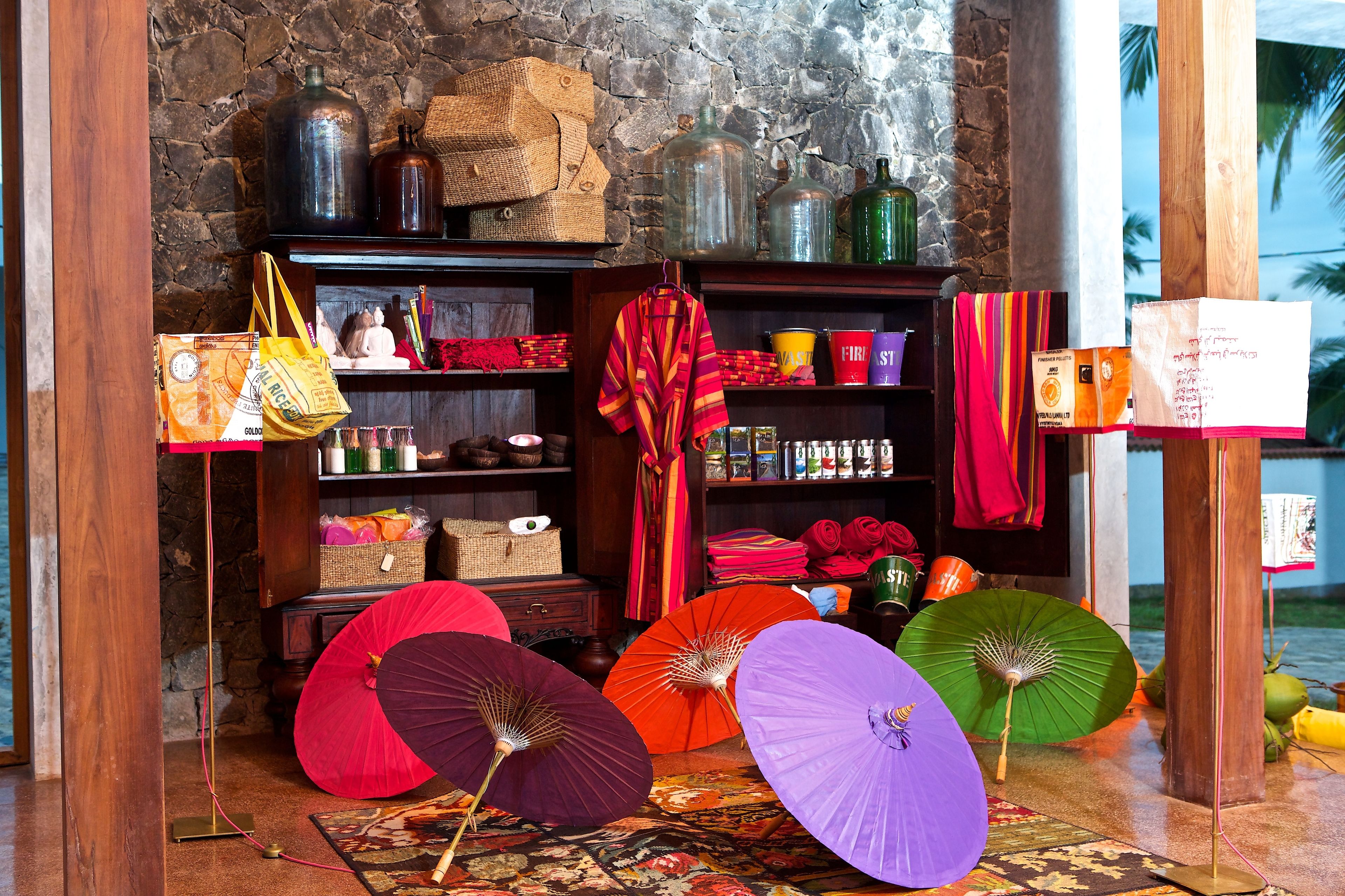 A room with a stone wall, wooden shelves with various items, and colorful umbrellas.