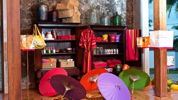 A room with a stone wall, wooden shelves with various items, and colorful umbrellas.