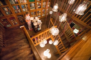 Uma biblioteca com estantes de madeira e luminárias pendentes.