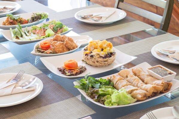 Una mesa de comedor con varios platos de comida, incluyendo ensaladas, rollitos primavera y otros manjares.