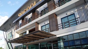 A modern building with a prominent "SCHOOL" sign, large windows, and a covered entrance area with steps. - Socool Grand Hotel (Nang Rong)