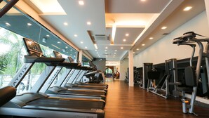 A gym with treadmills, exercise machines, and a wooden floor. - Socool Grand Hotel (Nang Rong)