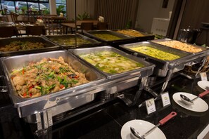 A buffet with various dishes, including stir-fried chicken, vegetable soup, and rice.